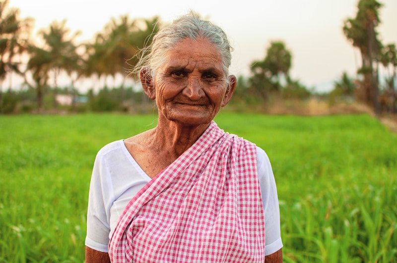 an old woman standing in a field of green grass
