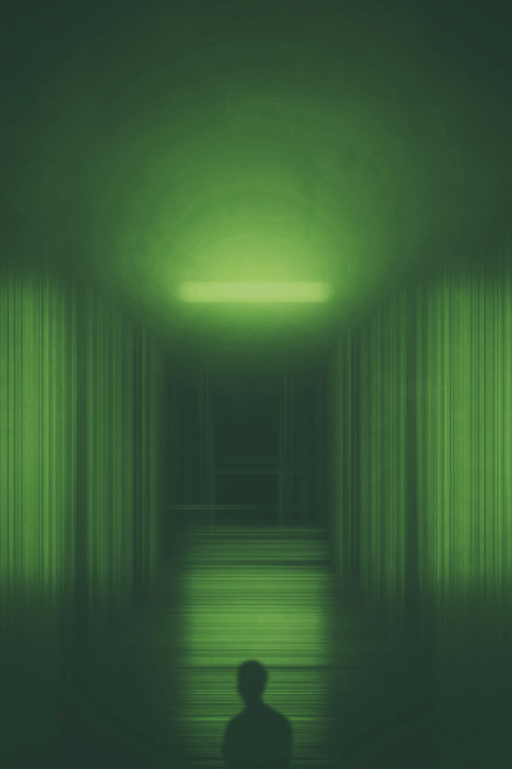 una persona in piedi in una stanza buia con una luce verde
