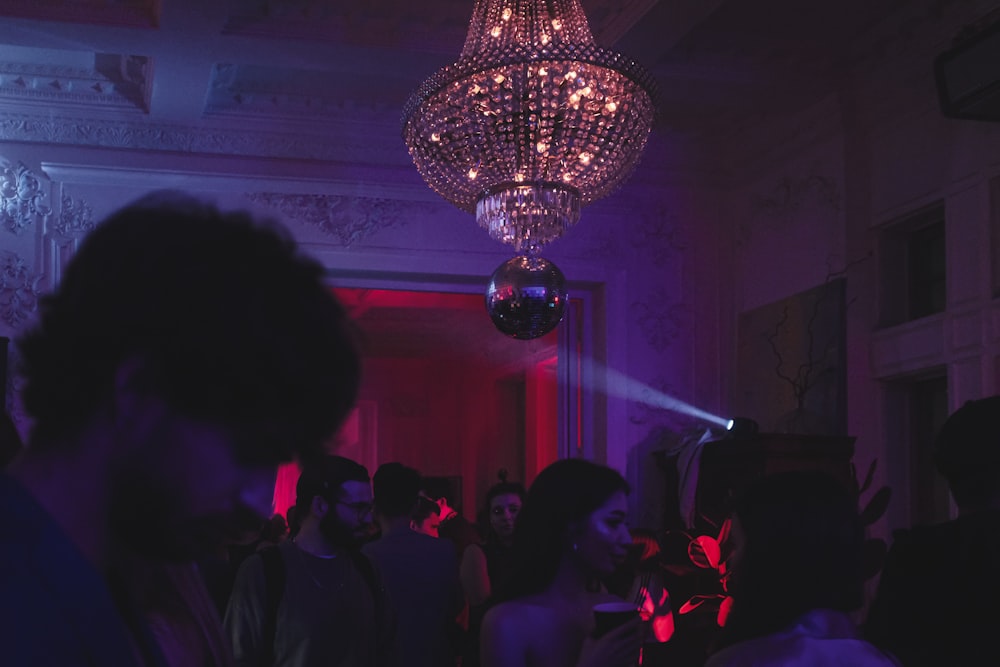 a group of people in a room with a chandelier