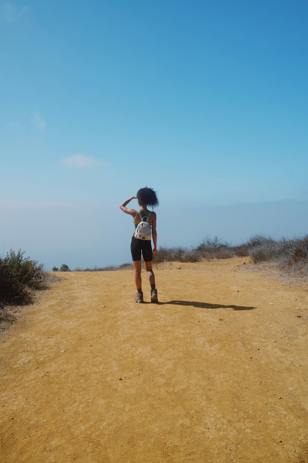 a woman standing in the middle of a dirt road