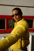 Model wearing layered gold necklaces and bold hoop earrings against a graffiti wall backdrop.