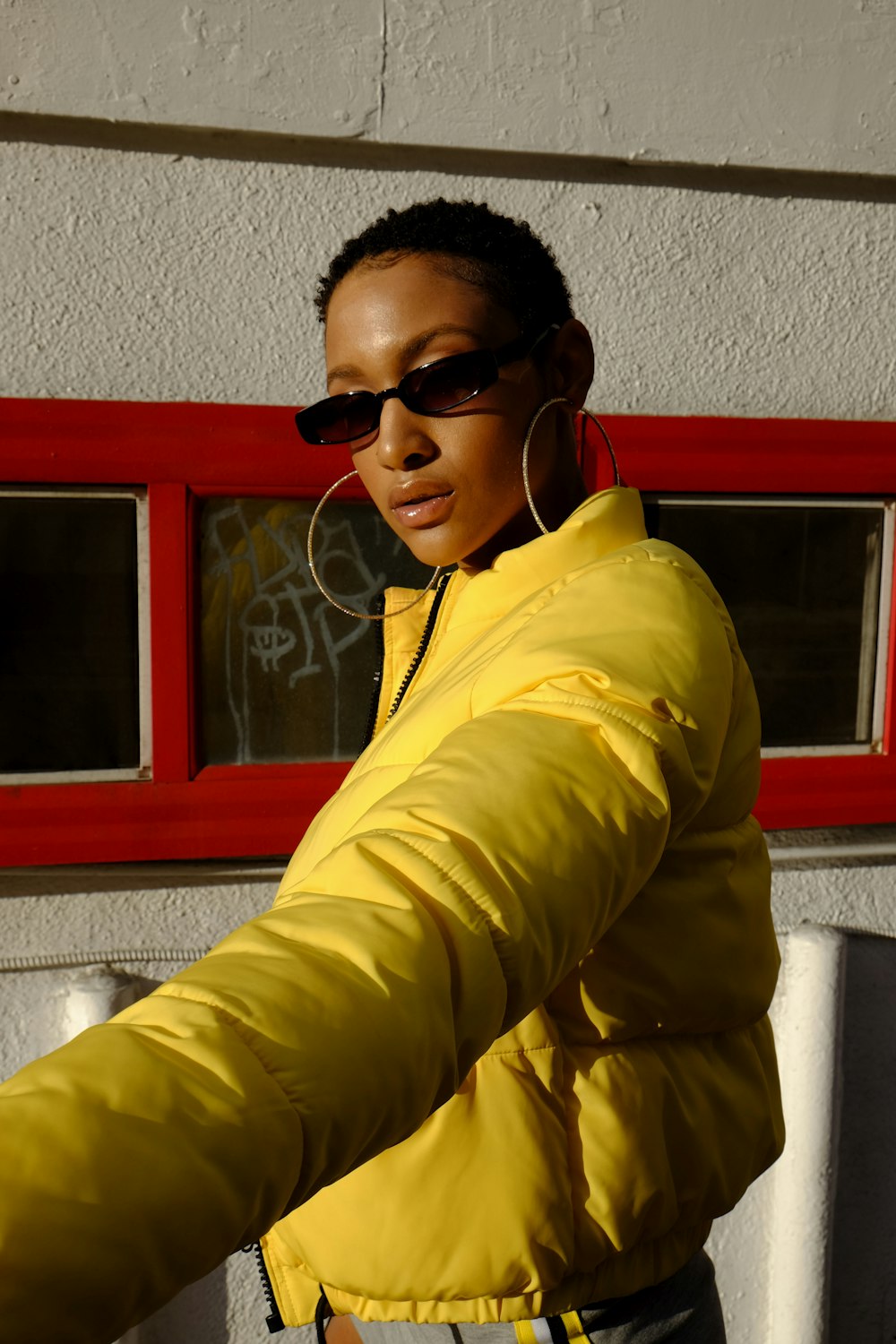 Una donna in giacca gialla e occhiali da sole