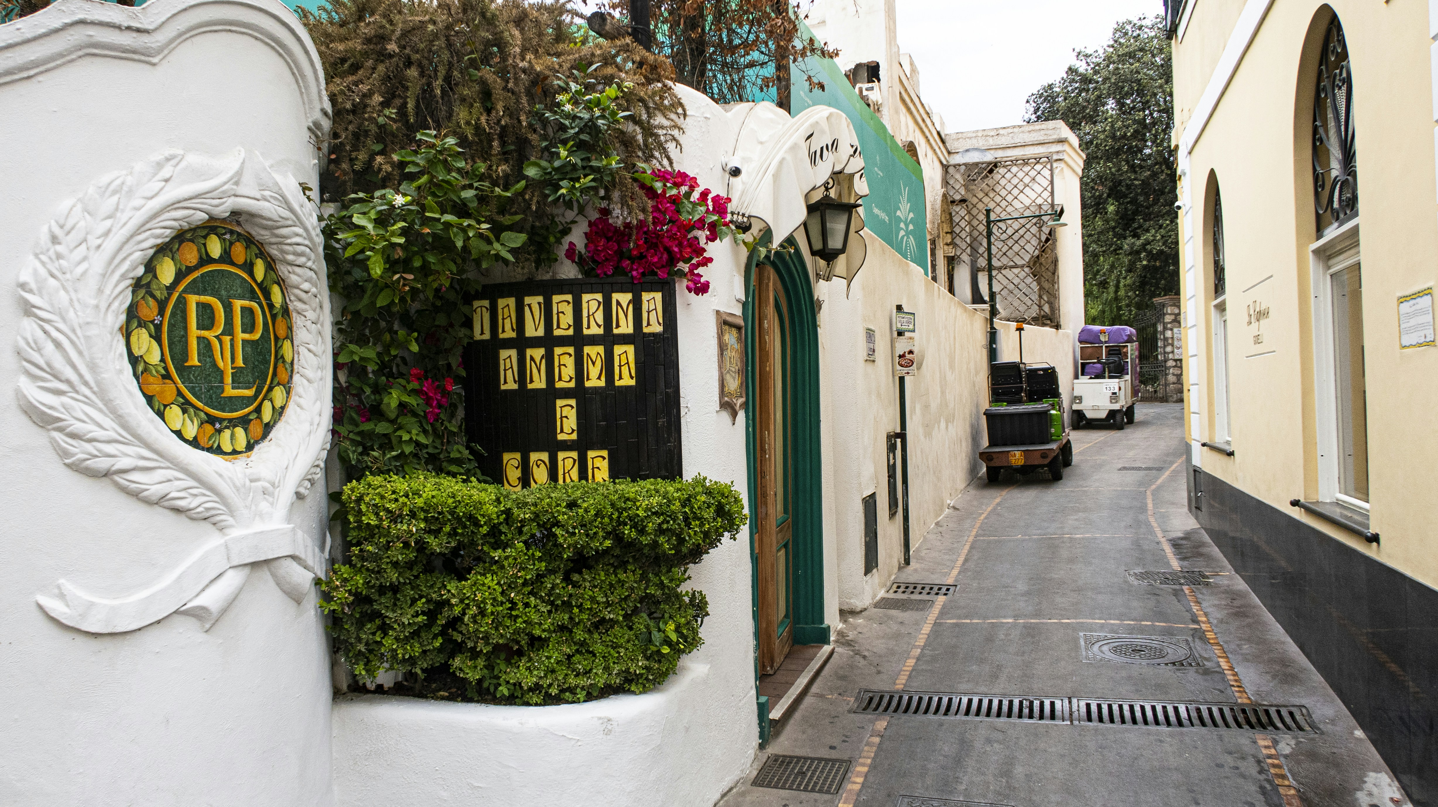 a narrow street with a sign on the side of it, Street in Capri Italy 