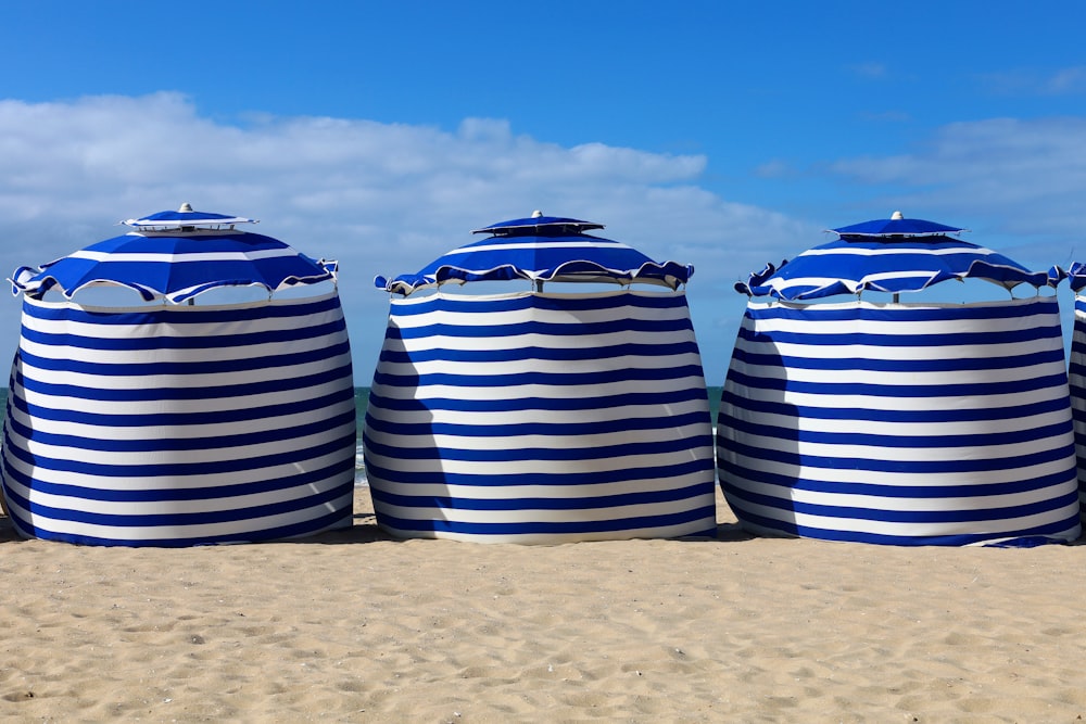 uma fileira de guarda-sóis listrados azuis e brancos sentados no topo de uma praia de areia