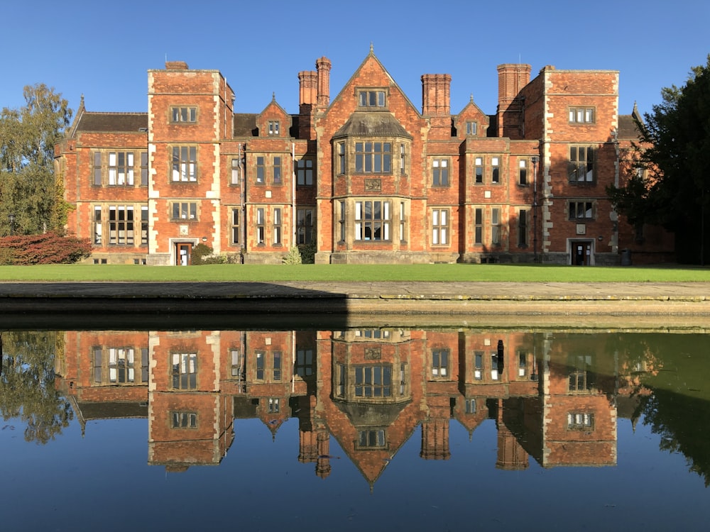 a large brick building with a lake in front of it