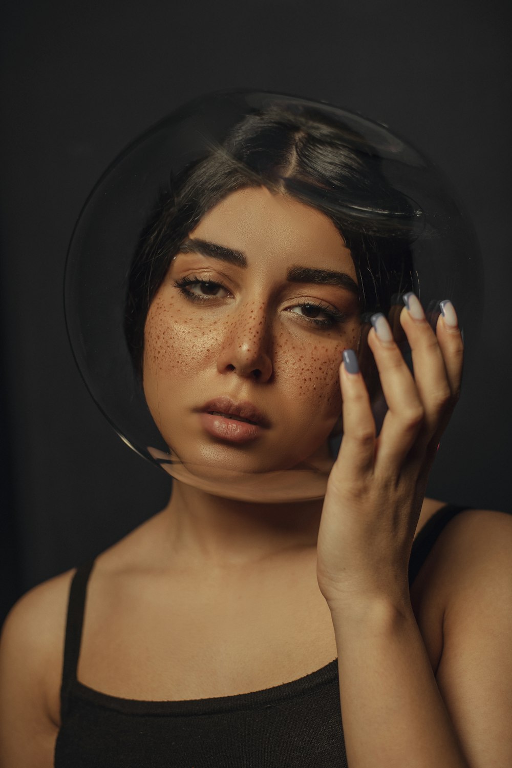 a woman with freckles on her face holding her hand to her face