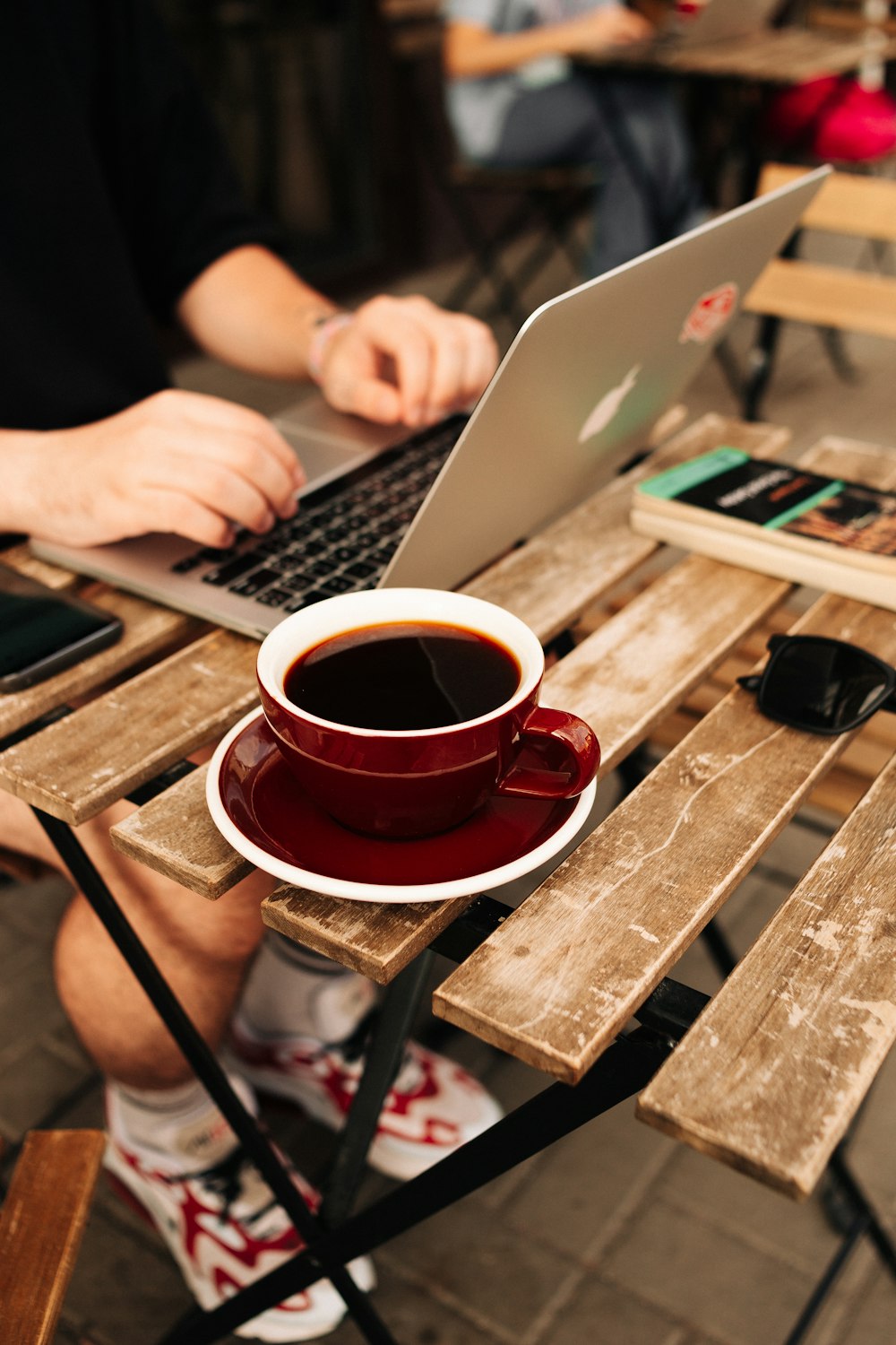 eine Person, die mit einem Laptop und einer Tasse Kaffee an einem Tisch sitzt