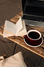 A cozy workspace with books, a laptop, and a warm cup of tea by a window.