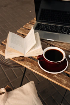 A cozy workspace with open books, a laptop, and a cup of coffee, symbolizing literary translation.
