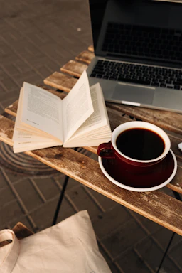 A warm, inviting workspace with books, a laptop, and a cup of coffee, reflecting a thoughtful and creative atmosphere.