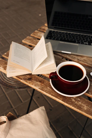 A cozy workspace with books, a laptop, and a cup of coffee, reflecting a creative publishing environment.