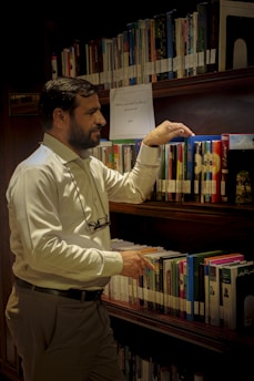 a man standing in front of a book shelf filled with books