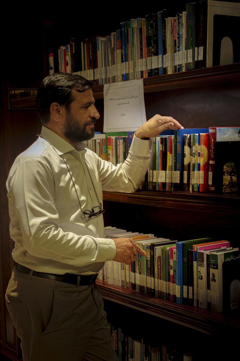 a man standing in front of a book shelf filled with books