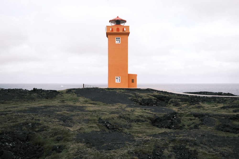 a large orange lighthouse on top of a hill