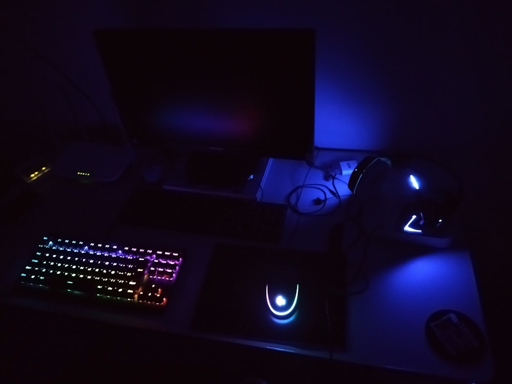 a desk with a keyboard, mouse and monitor lit up in the dark