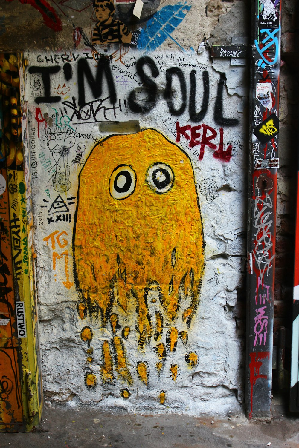 a graffiti covered wall with a yellow jellyfish on it