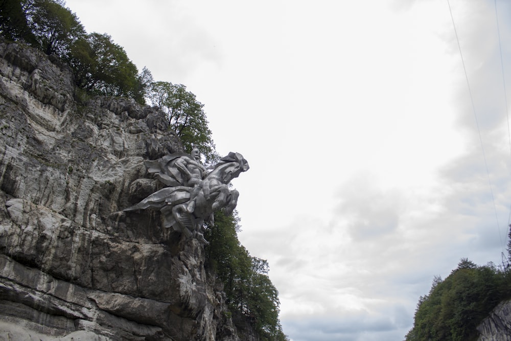a statue of a man riding a horse on the side of a cliff