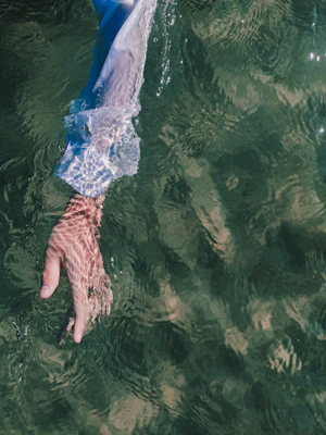 a person's hand reaching for a frisbee in the water