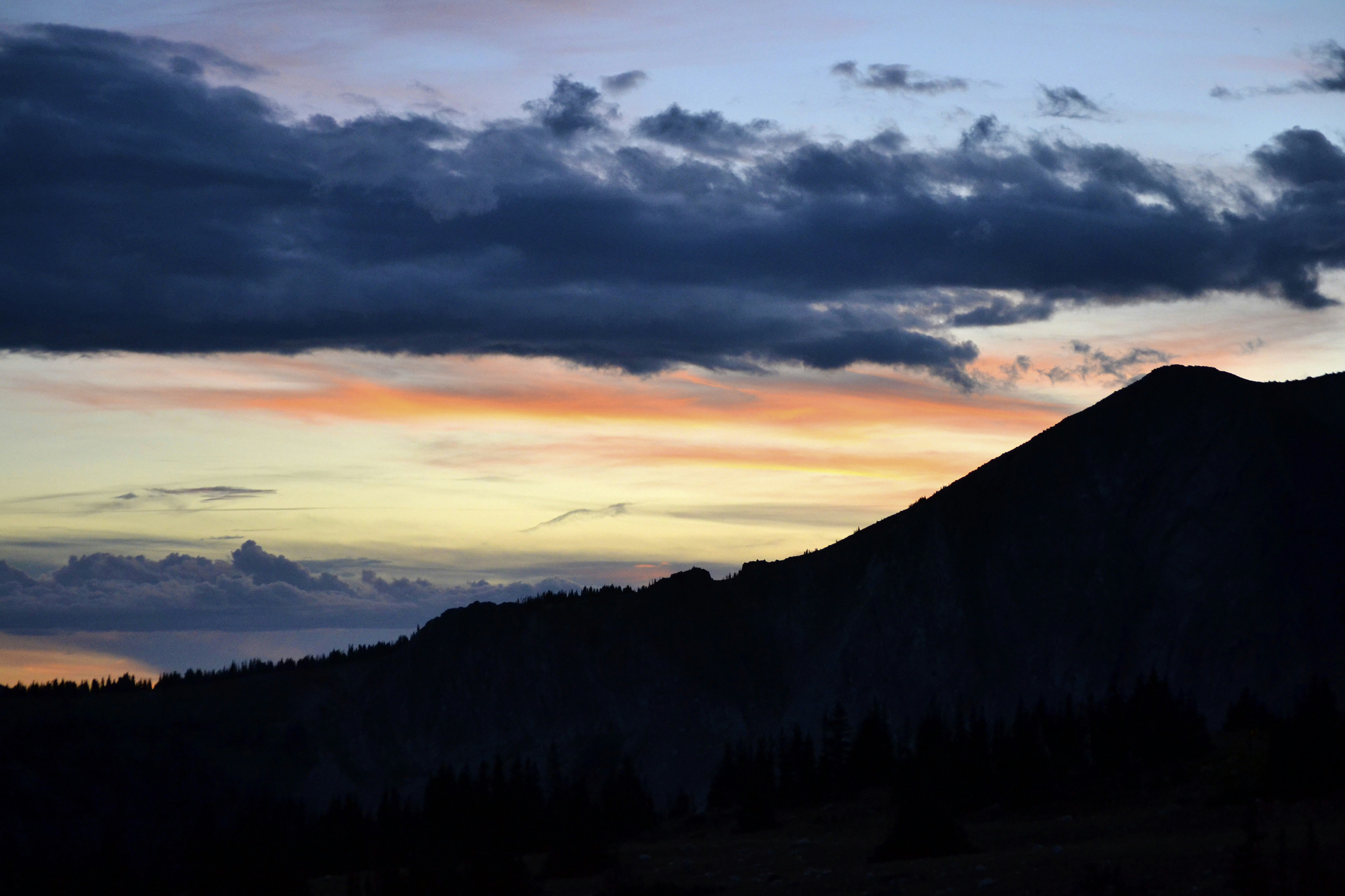 a mountain is silhouetted against a cloudy sky