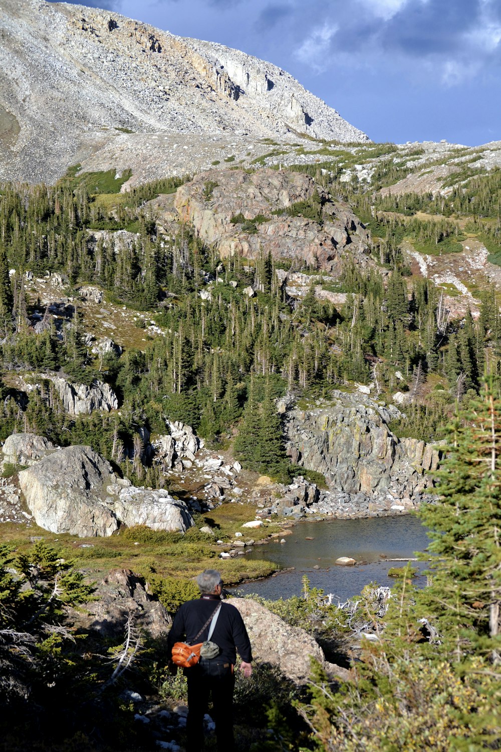 a man hiking up a mountain with a lake in the foreground