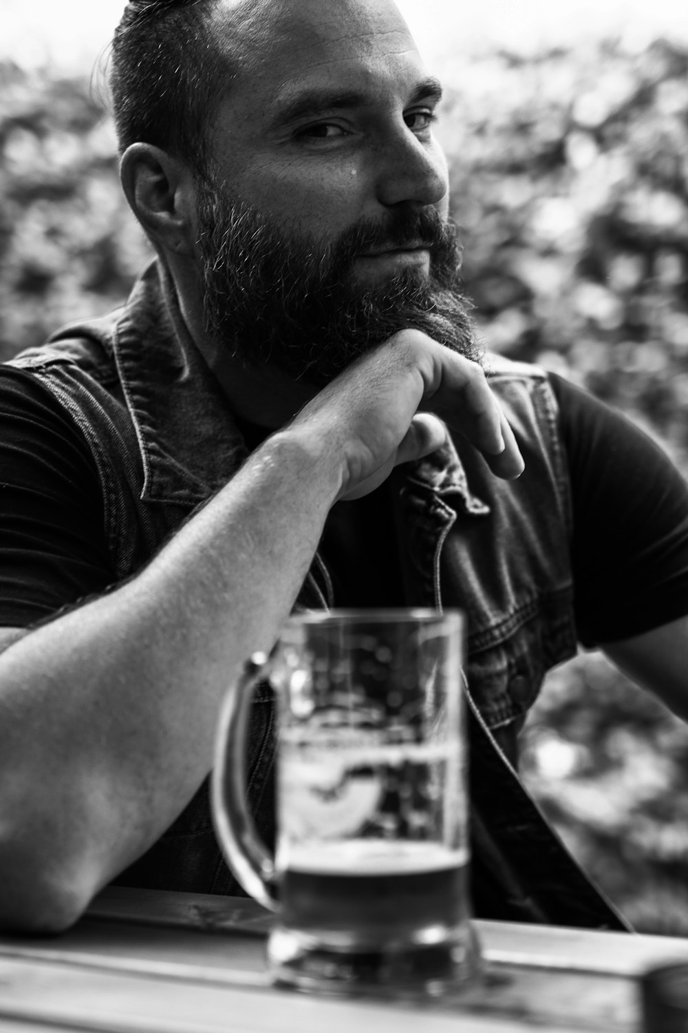 Un uomo seduto a un tavolo con un bicchiere di birra