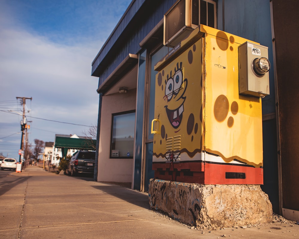 a yellow and red box sitting on the side of a building