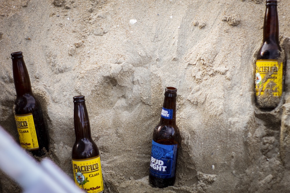 a group of beer bottles sitting on top of a sandy beach