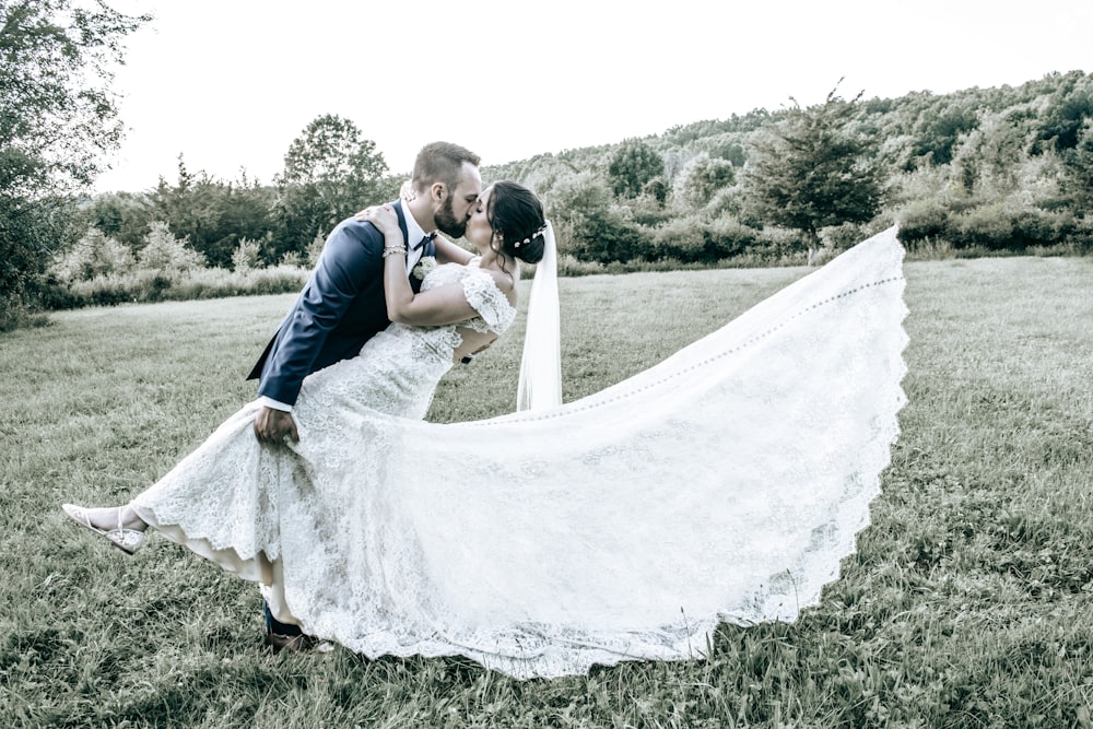 a bride and groom kissing in a field