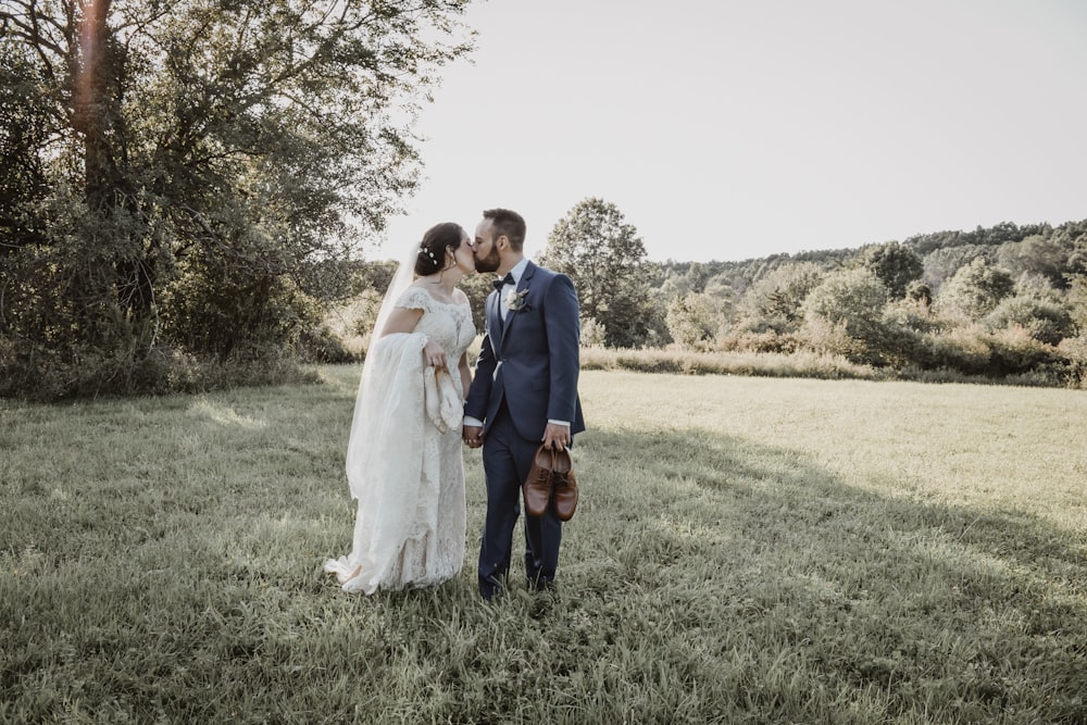a bride and groom kissing in a field