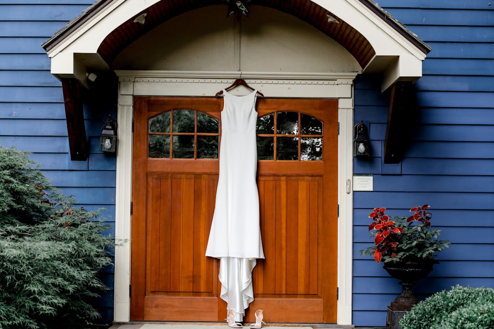 a white dress hanging on a wooden door