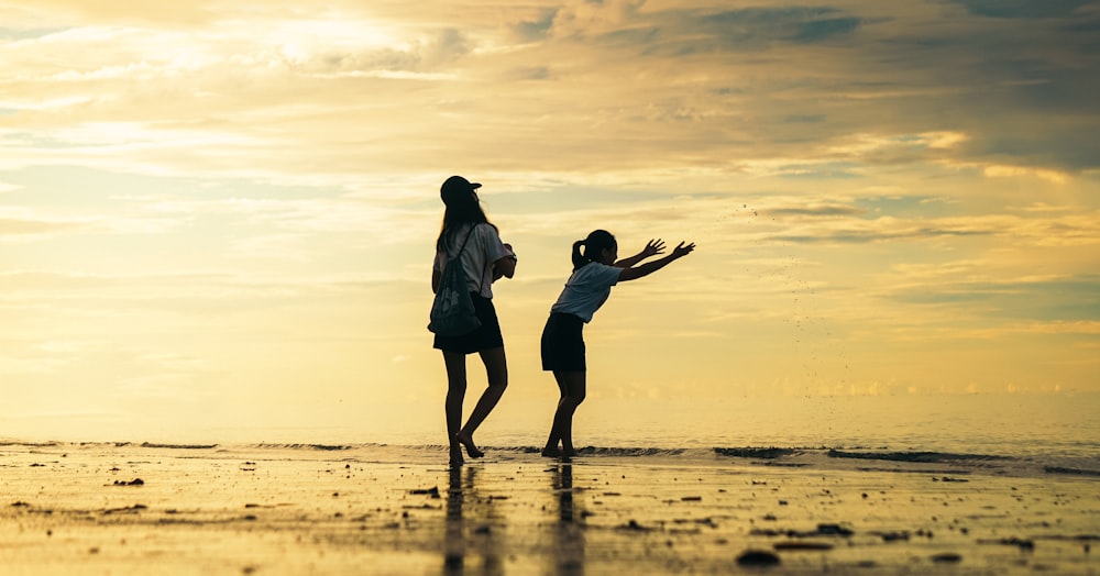 a couple of people standing on top of a beach