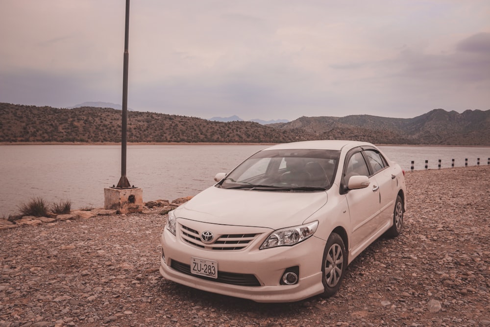 a white car parked next to a body of water