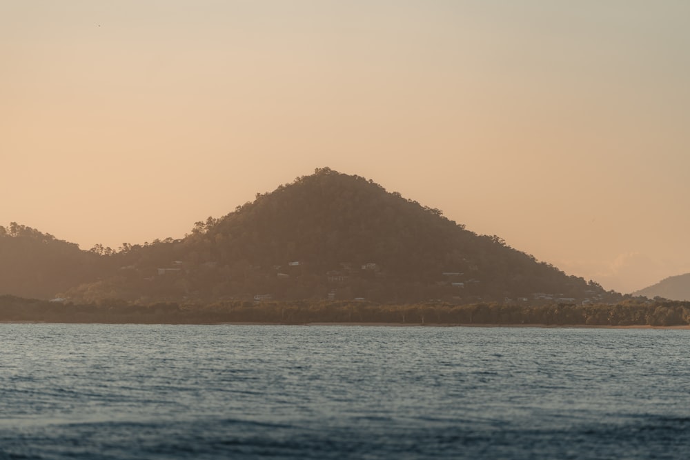 ein großes Gewässer mit einem Berg im Hintergrund