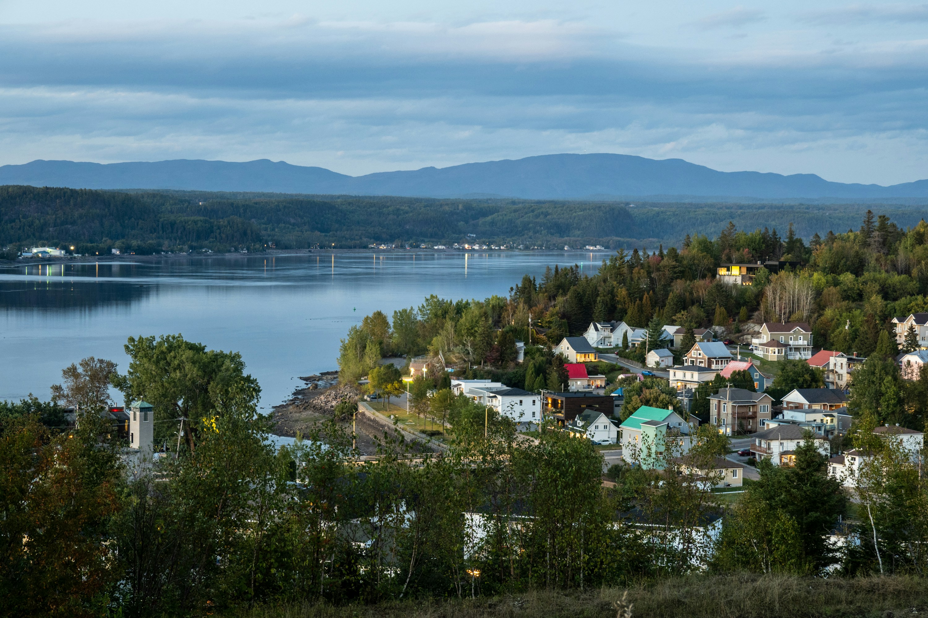 a view of a small town with a lake and mountains in the background