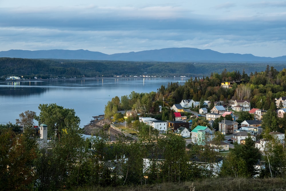 a view of a small town with a lake and mountains in the background