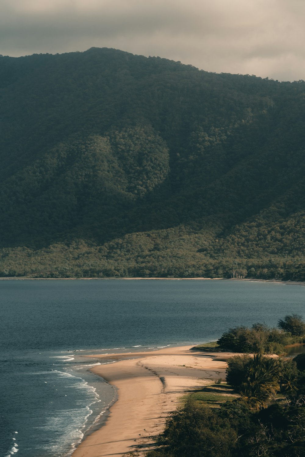 a large body of water sitting next to a lush green hillside