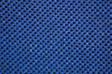 A close-up view of a textured surface composed of a grid pattern with small, raised bumps. The surface is predominantly blue and has a fabric-like appearance, suggesting it could be a piece of material or upholstery.