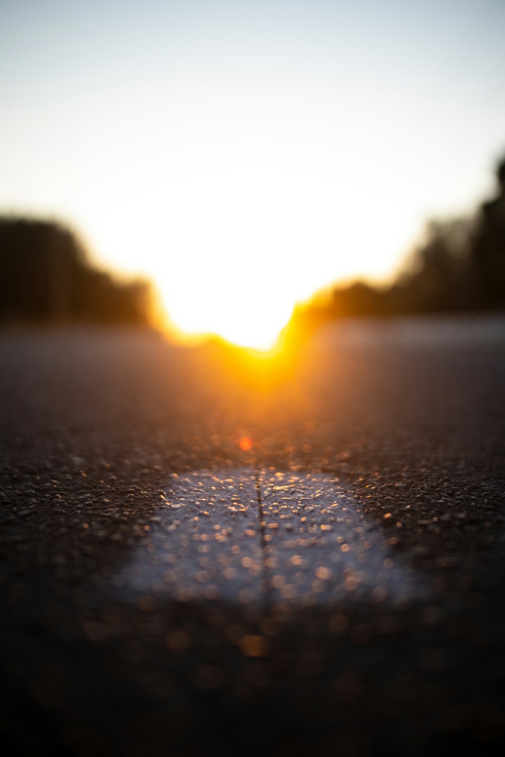 the sun is setting over a street with a line in the middle of the road