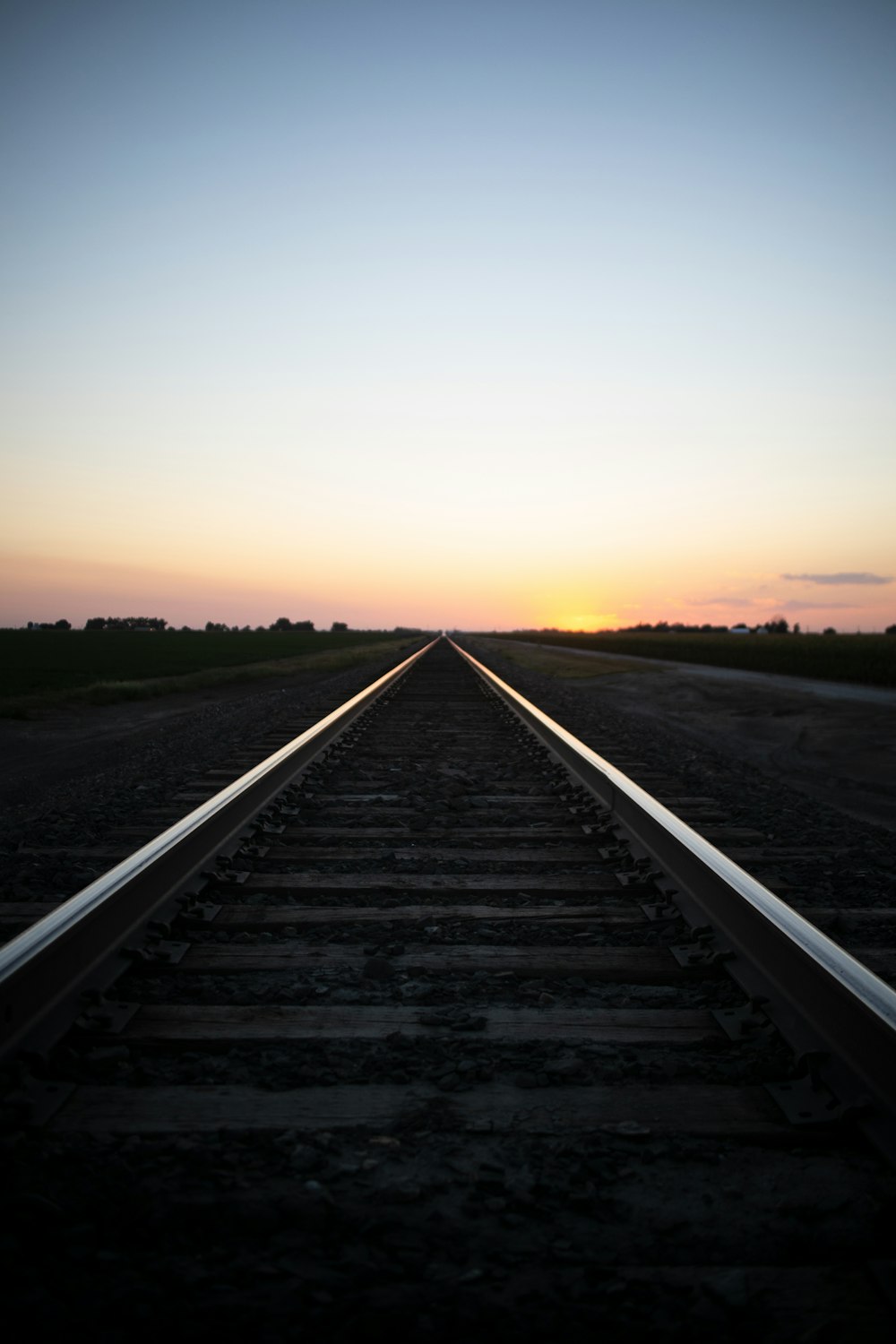 a train track with the sun setting in the distance