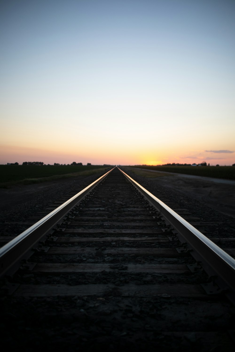 uma linha de trem com o pôr do sol à distância