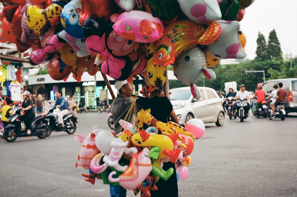 a person holding a bunch of balloons on a street