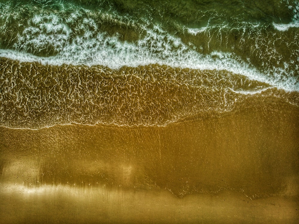 uma vista aérea de uma praia com ondas entrando