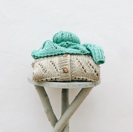 a knitted hat sitting on top of a wooden stool