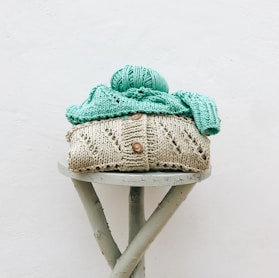 a knitted hat sitting on top of a wooden stool