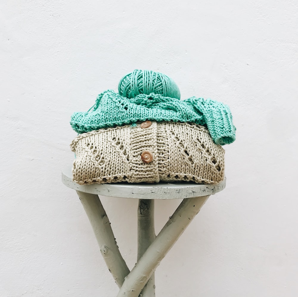 a knitted hat sitting on top of a wooden stool