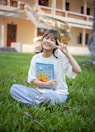 a young girl sitting in the grass holding a book
