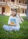a young girl sitting in the grass holding a book