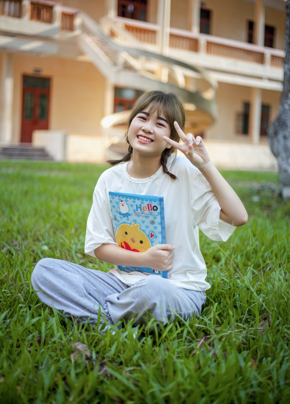 a young girl sitting in the grass holding a book
