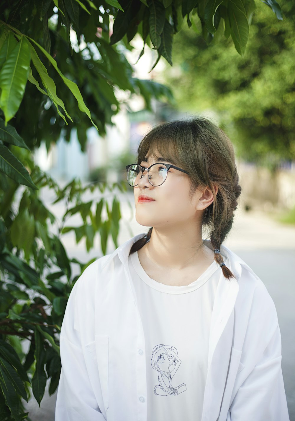 a woman wearing glasses standing next to a tree