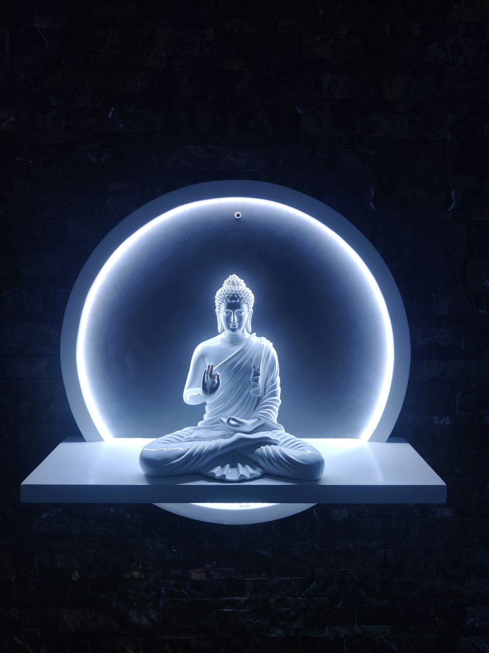 une statue de Bouddha assise devant une lumière bleue
